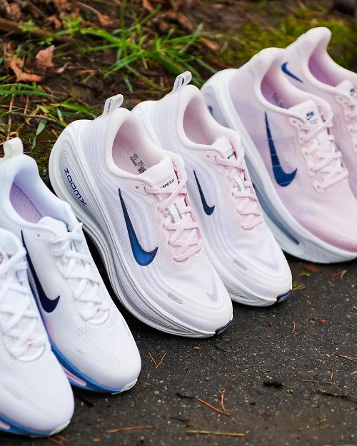 3 pink nike shoes lined up next to each other outside