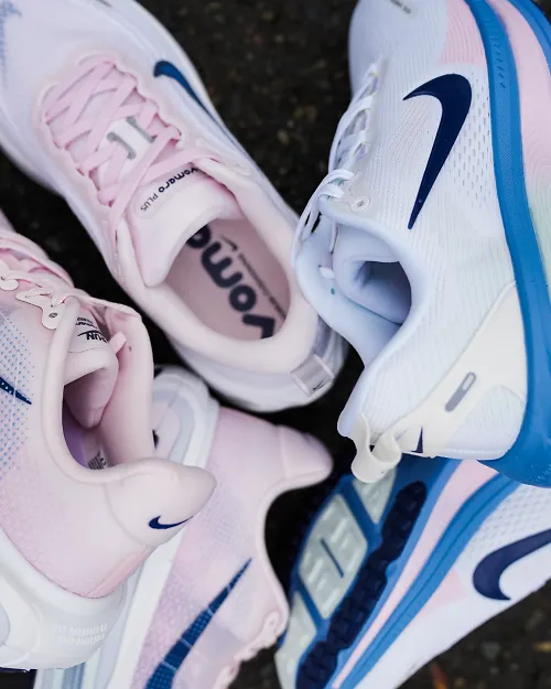 a pile of pink nike shoes laying on each other outside